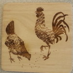 A wooden coaster with two roosters on it.