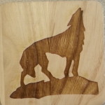 A wooden picture of a wolf standing on top of a hill.