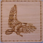 A wooden picture of an eagle flying.